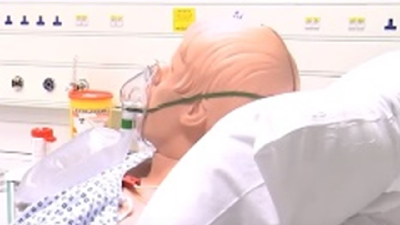 Mannequin in bed in hospital room with oxygen mask